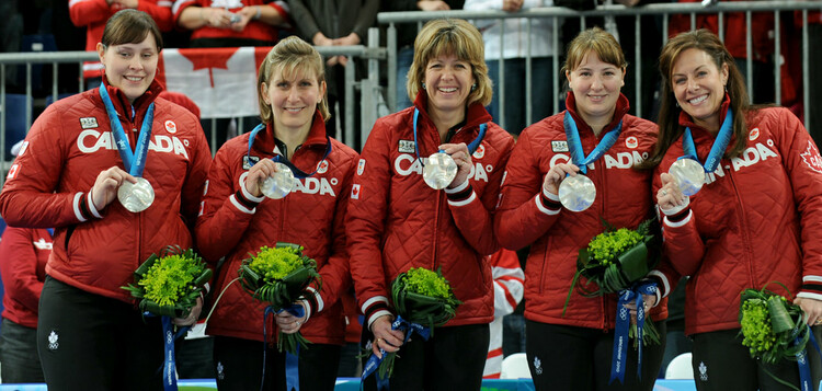 Group photo of women curler team with medals.