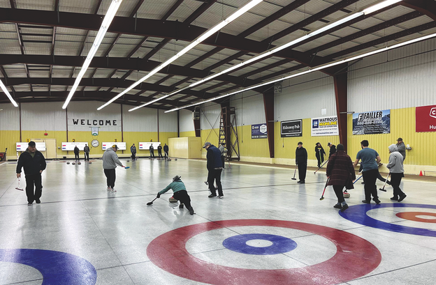 Curling rink action shot with multiple teams on multiple lanes.