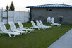 Row of lounge chairs located outside of the pool within the grounds.