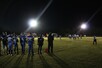 Football sideline view of football field with players at night.