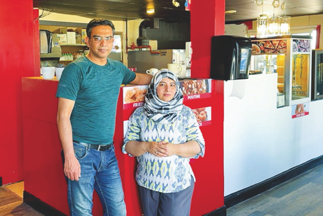 Local business owners posing in their pizza shop.