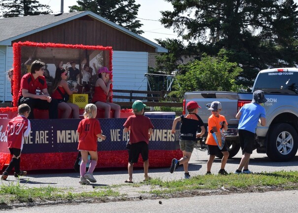 Colourful parade float with children cheering and watching.