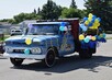 Blue vintage truck with balloons attached as part of the parade.