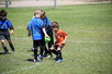 Three kids playing soccer on a soccer field.