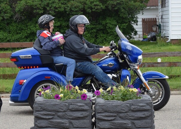 Three-wheeler parade float with riders handing out bubble gum to viewers.