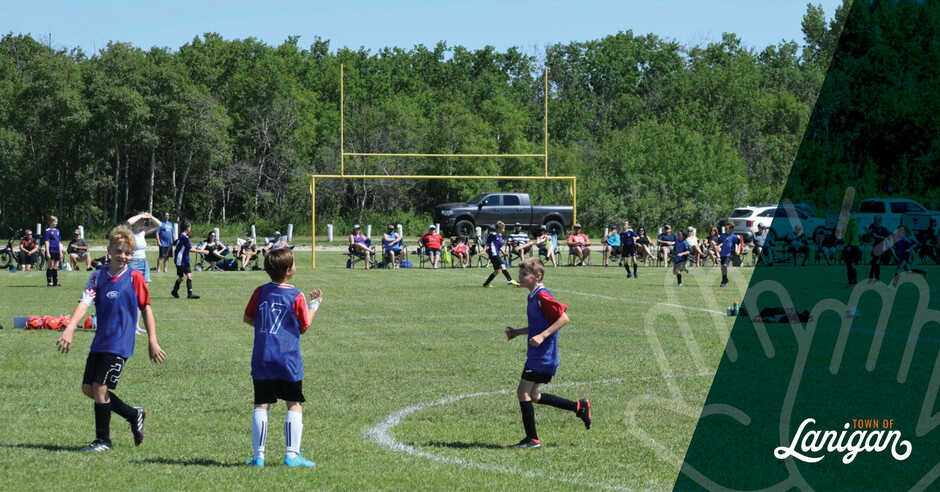 Children playing soccer at the soccer field with spectators watching.